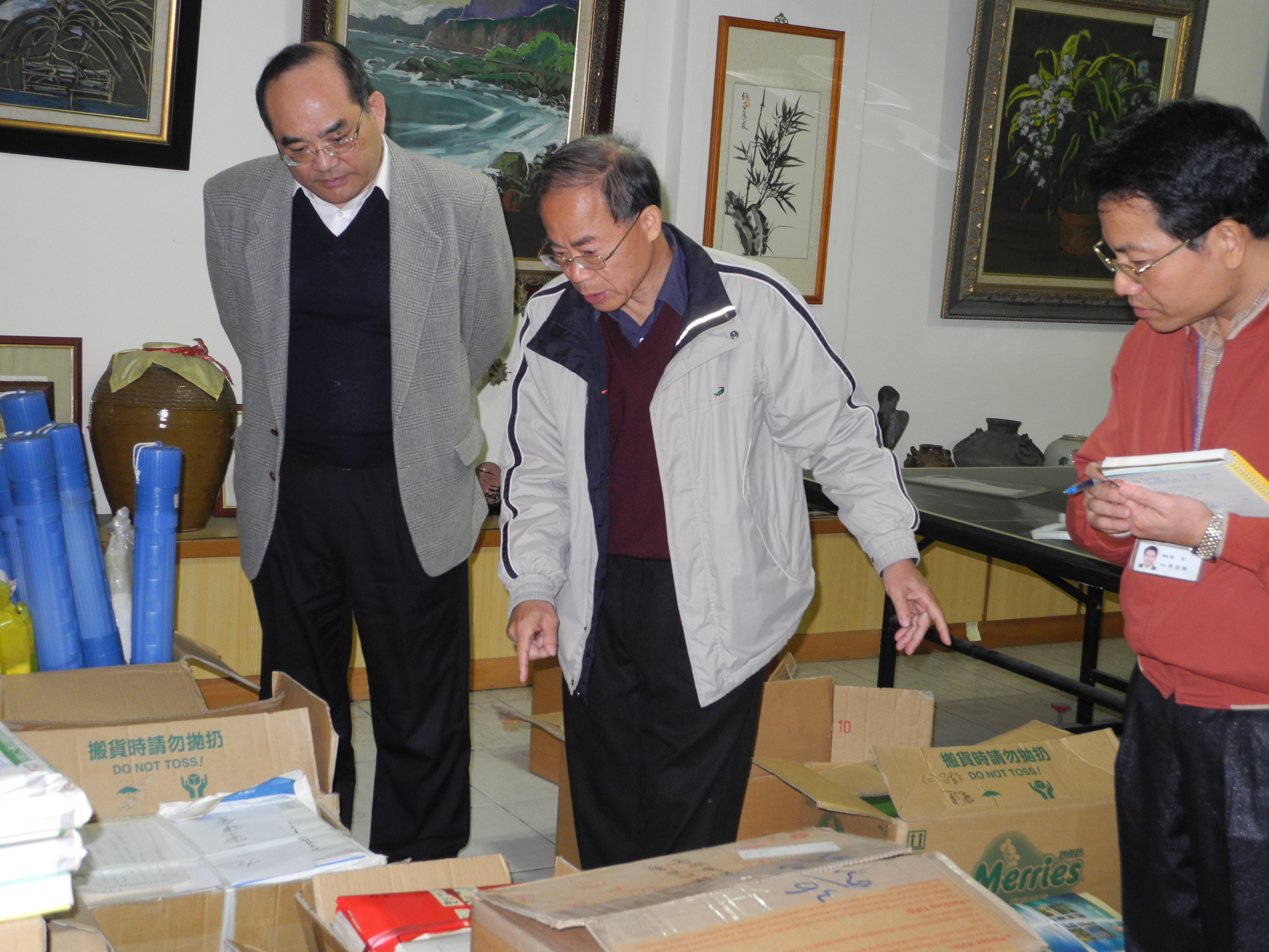 本館張館長鴻銘（左）與林組長明洲（右）仔細聆聽前921重建會吳副執行長崑茂（中）介紹擬捐贈圖書資料內容