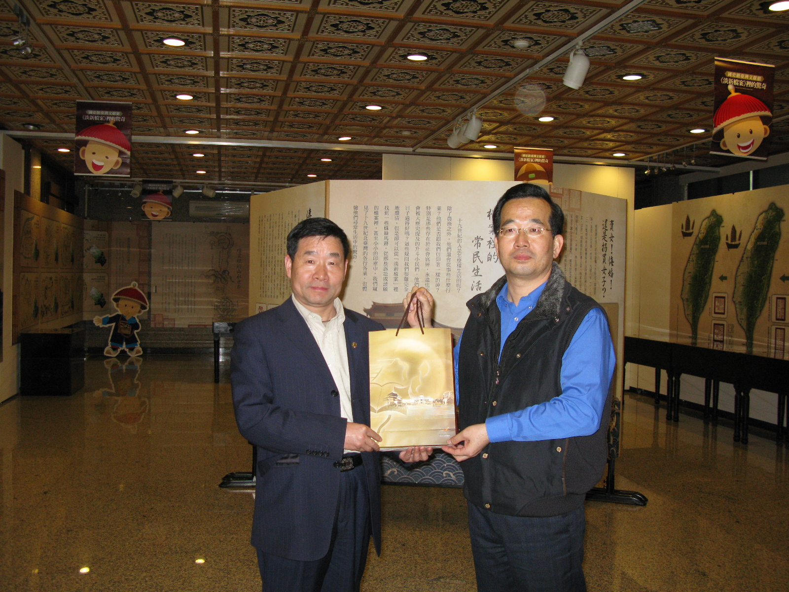 本館整理組洪編纂瑞豐(右)贈送福州市檔案學會參訪團李理事長運啟(左)本館出版品