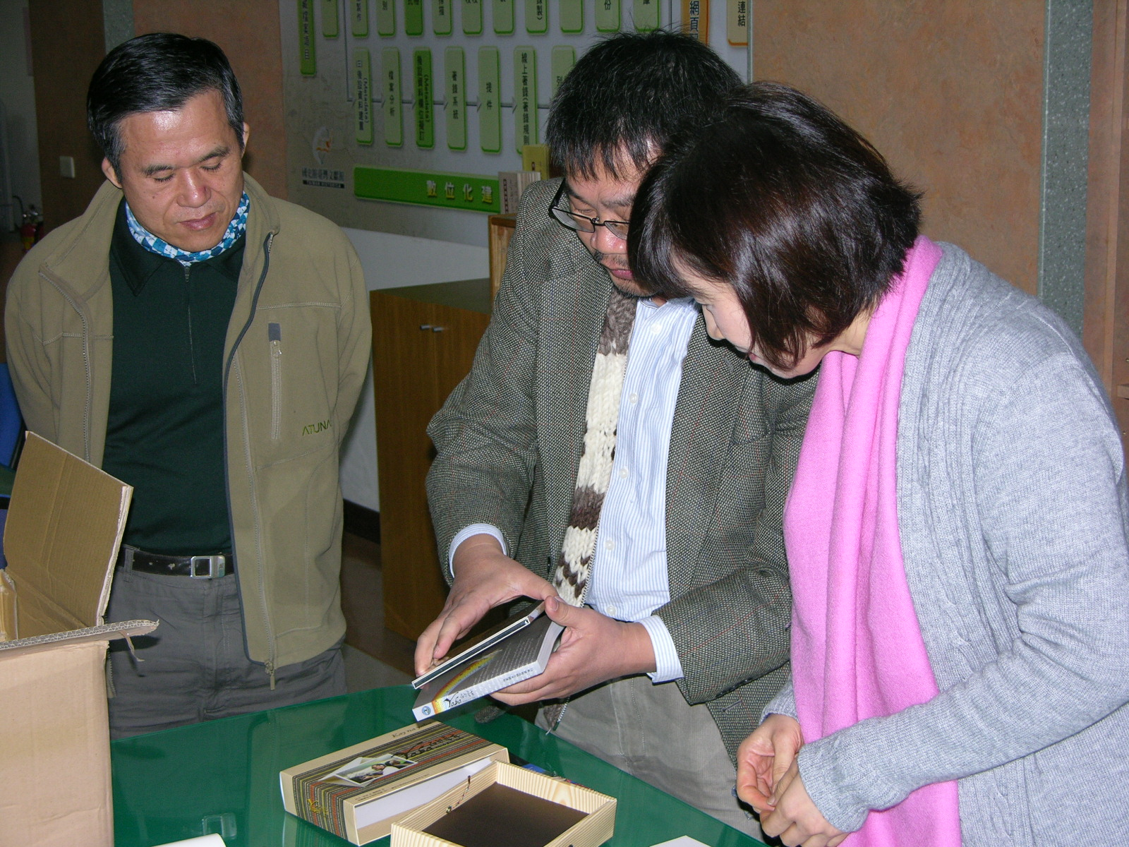 靜宜大學林益仁主任(右二)向簡組長秀昭(右一)介紹該校出版品