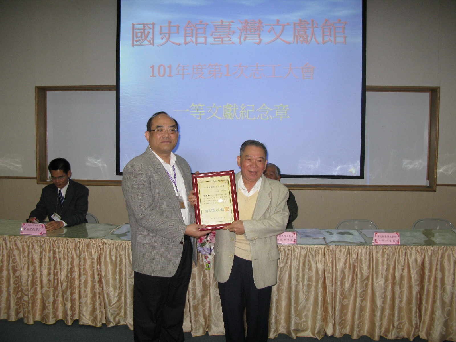 本館張館長鴻銘(左)頒發一等文獻志工紀念章及獎牌予本館志工李默默先生(右)