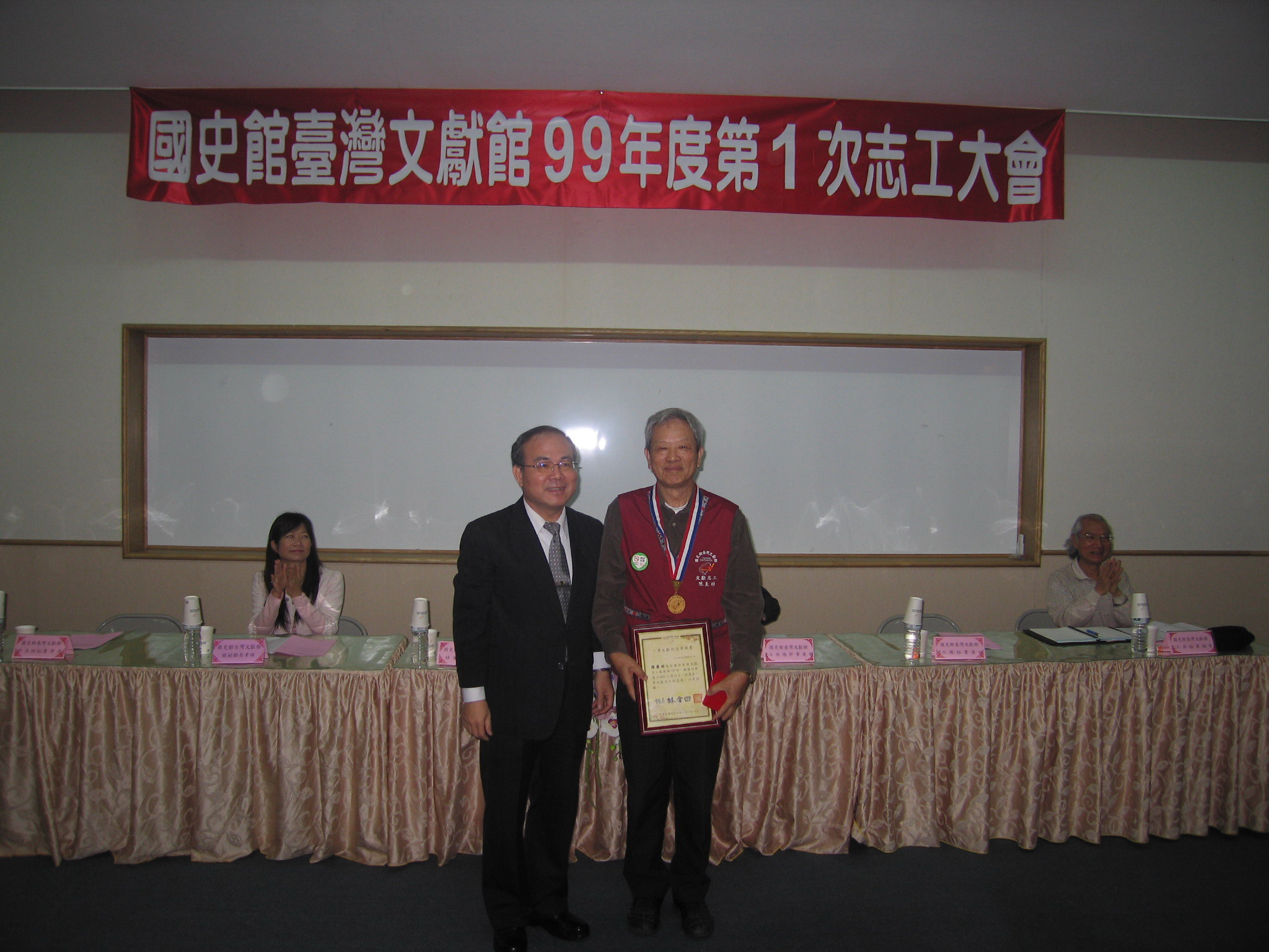 林館長金田(左立)頒發本館一等文獻紀念章及證書與志工隊陳秘書義助﹝右立﹞