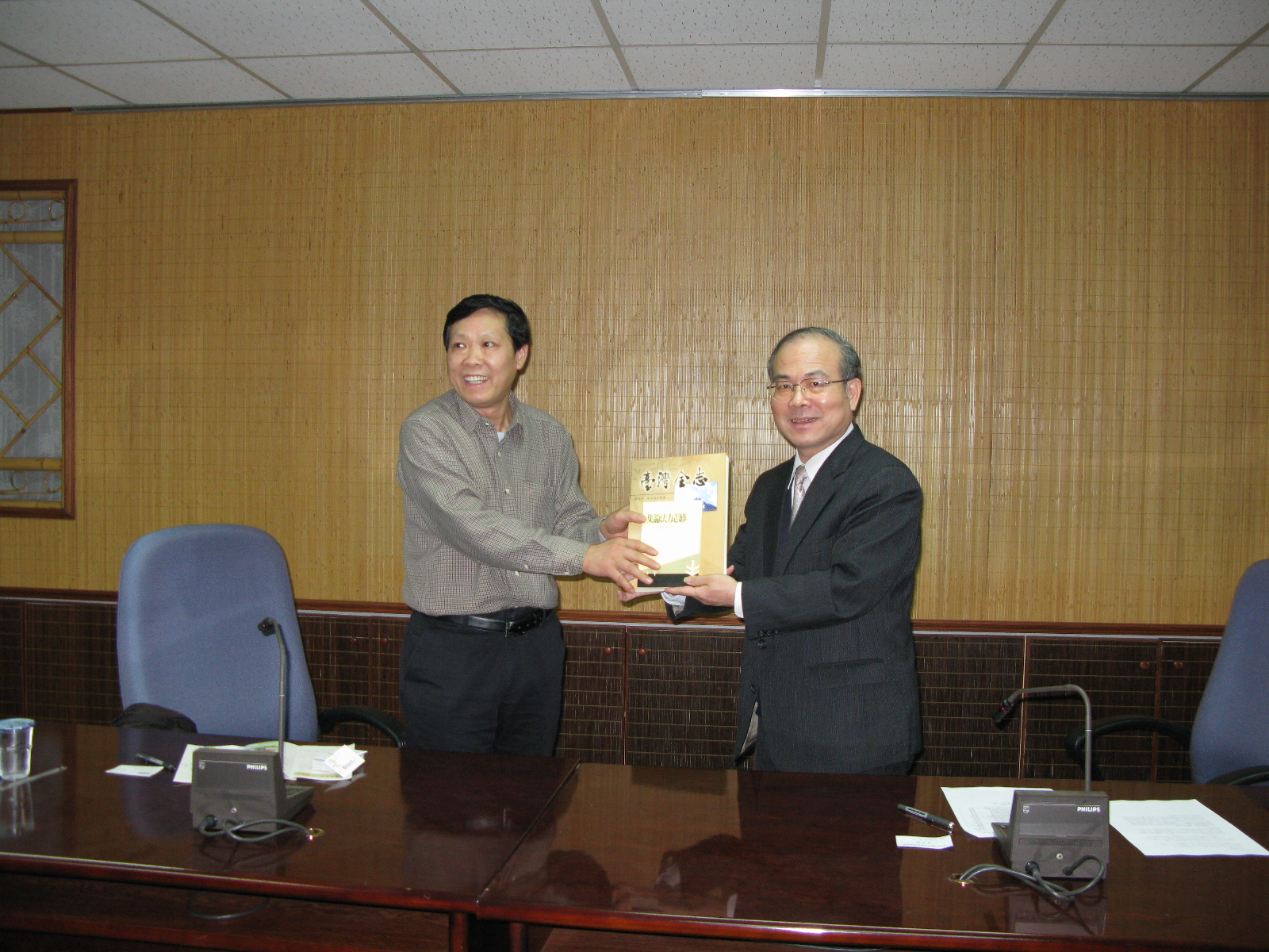 館林館長金田(右)贈送浙江省台州市地方志交流團王主任永獻(左)本館出版品
