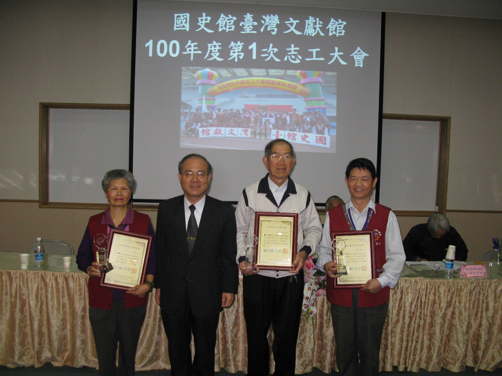本館林館長金田(左3)頒發二等文獻志工紀念章及證書與獎牌予本館志工洪枰女士(左1)、鄭玉祥先生(右2)、陳全旺先生(右1）